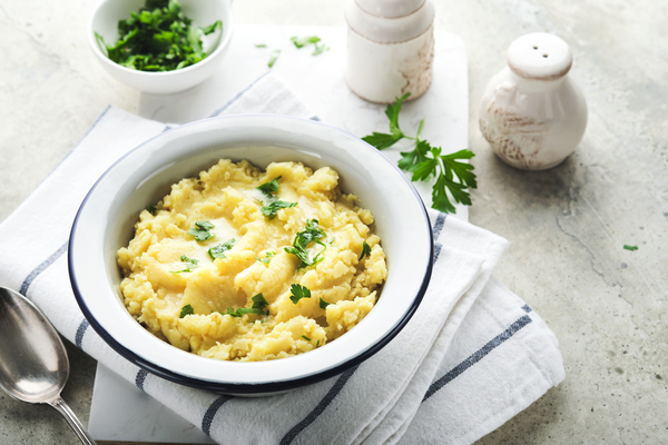 Mashed potatoes. Hot mashed potatoes with butter, fresh parsley herbs and pepper in bowl on slate, stone or concrete backgrounds. Delicious creamy mashed potatoes. Top view.